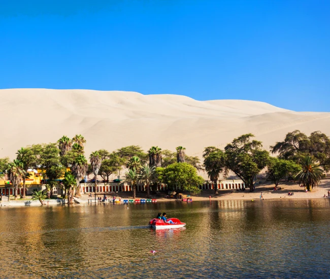 Huacachina Oasis Lagoon in Ica, Peru | Conde Travel Adventures Scenic view of the Huacachina Oasis lagoon surrounded by desert dunes in Ica, Peru | Conde Travel Adventures