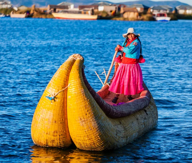 Uros Community Rowing Boat on Lake Titicaca | Conde Travel Adventures Person from the Uros community navigating a traditional reed boat on Lake Titicaca in southern Peru | Conde Travel Adventures