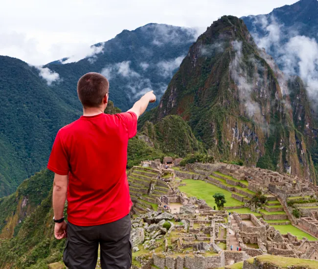 Is a private Machu Picchu tour worth it? Viewpoint of Machu Picchu in Peru Traveler pointing at Machu Picchu during a private Machu Picchu tour in Peru, showing the viewpoint and ancient Inca ruins.